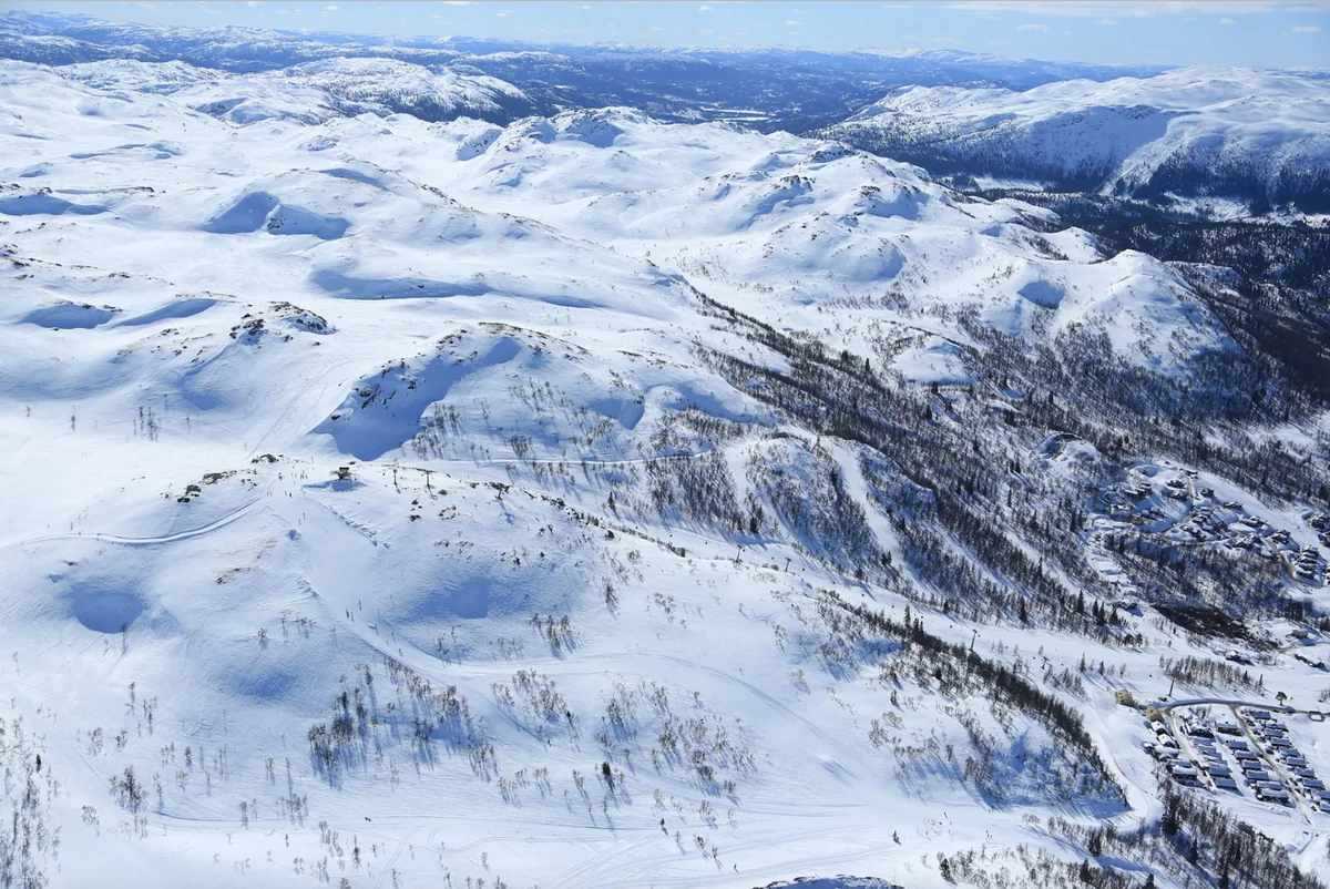 Snøkledt fjellandskap med preparerte løyper og heiser om vinteren
