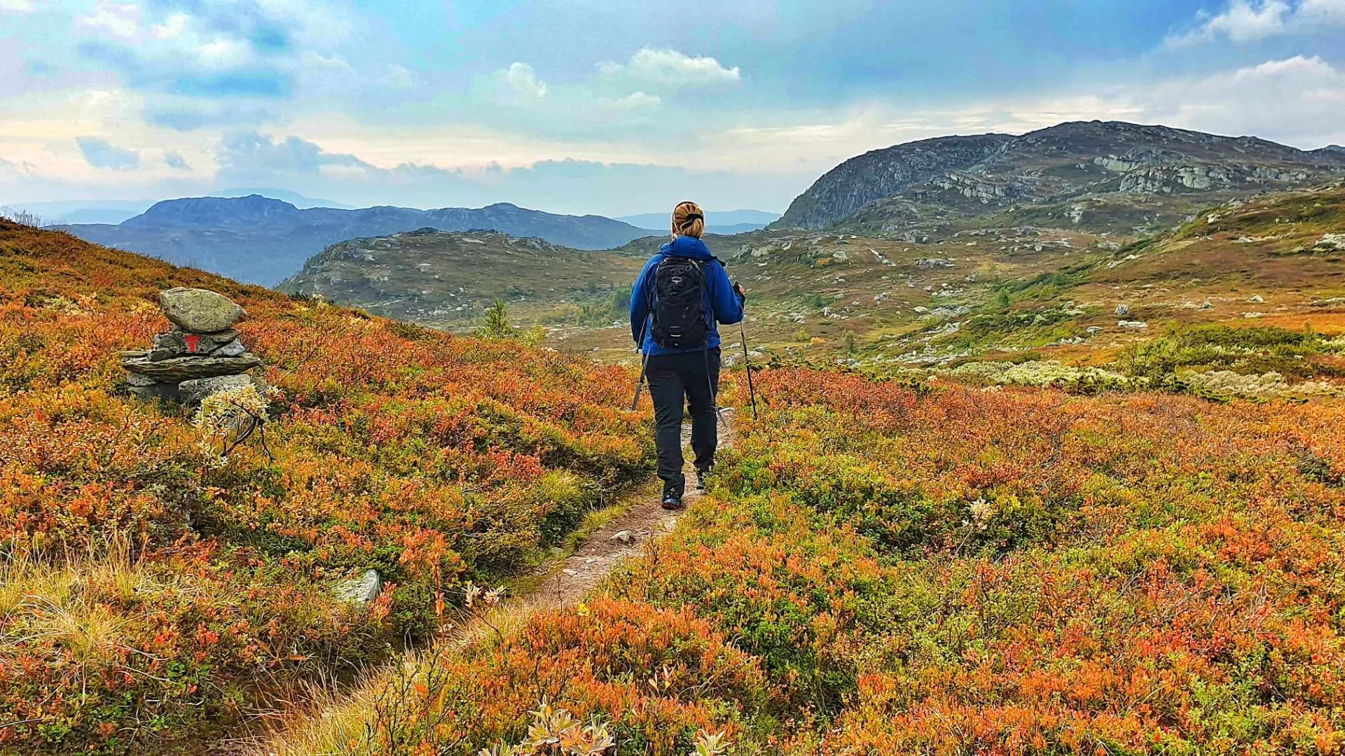 Vandrer på merket sti forbi steinvarde i oransje høstlyng