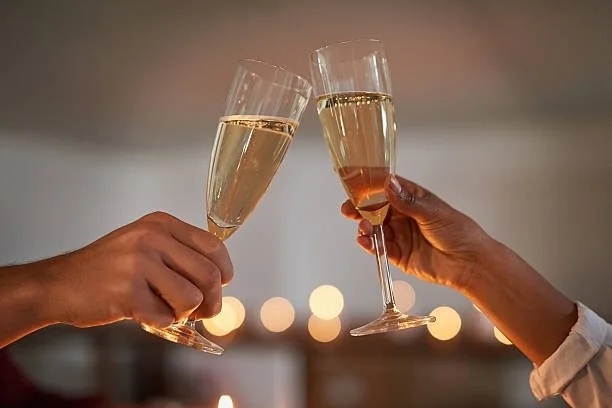 To personer skåler med champagneglass i varm restaurantbelysning